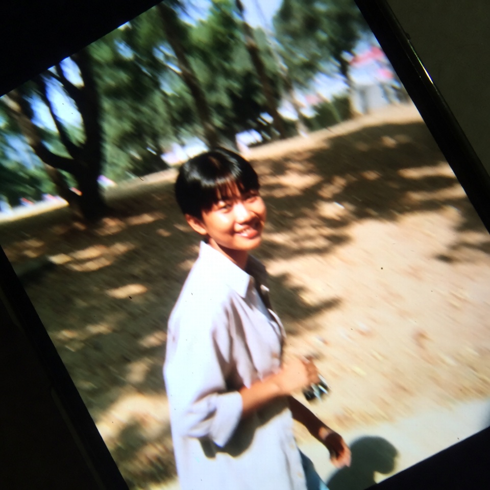 A person smiling warmly while enjoying a relaxed outdoor afternoon in natural daylight