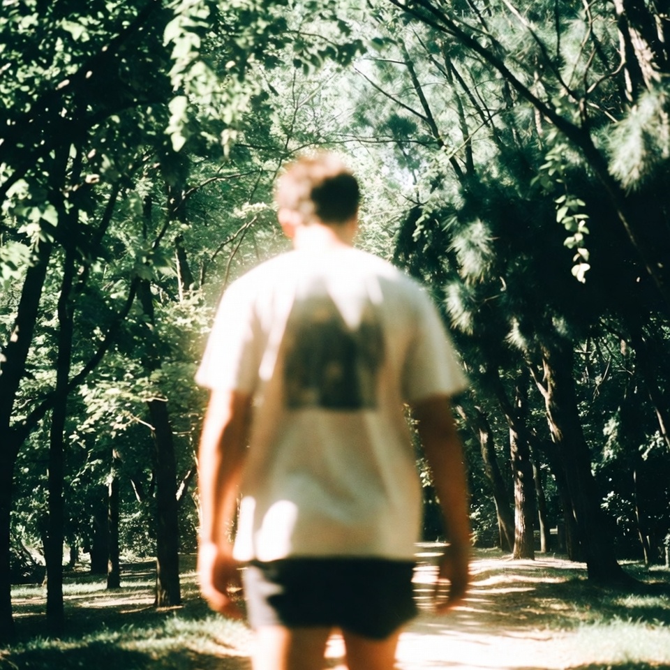Person taking a casual stroll along a sunlit park path during the day