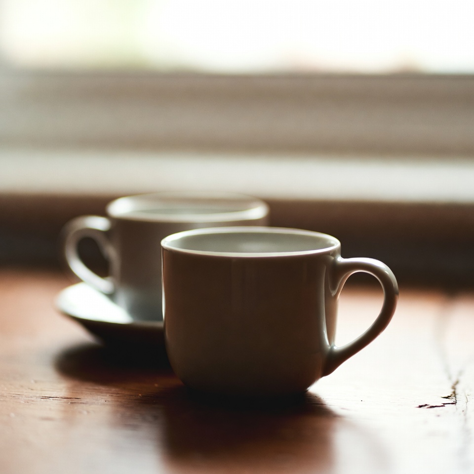 Two ceramic cups resting on a rustic wooden table during a relaxed chat